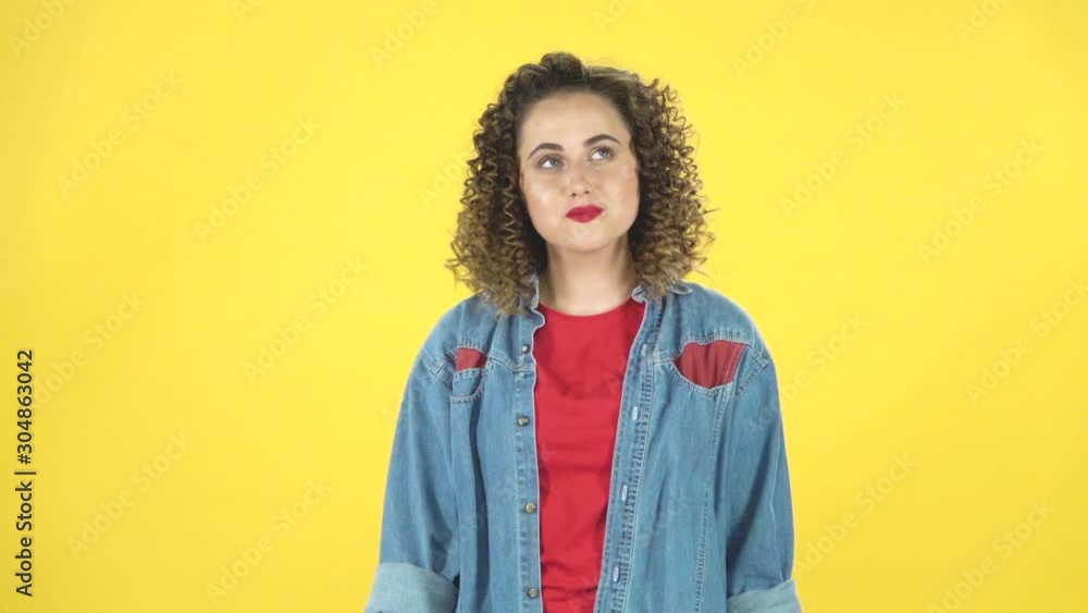 Lovely girl daydreaming and smiling looking up against on yellow background at studio, slow motion. Lovely girl daydreaming and smiling looking up against on yellow background at studio, slow motion.