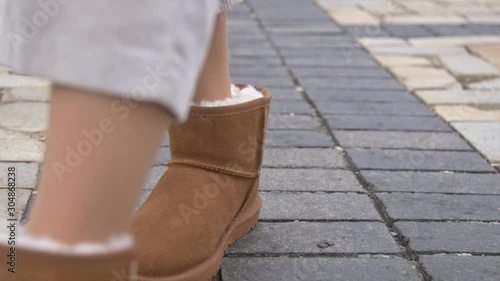 Close up Woman walking in brown ugg winter boots photo