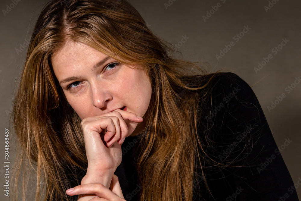 charming and cute young blonde girl on a gray background with a slightly sad expression charming and cute young blonde girl on a gray background with a slightly sad expression