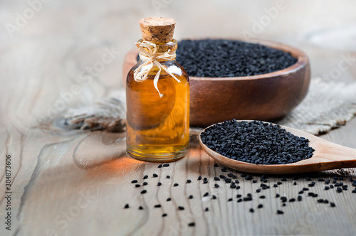 glass bottle of black cumin seeds essential oil , Nigella Sativa in spoon on wooden background. Organic herbal medicine for many diseases, black cumin
