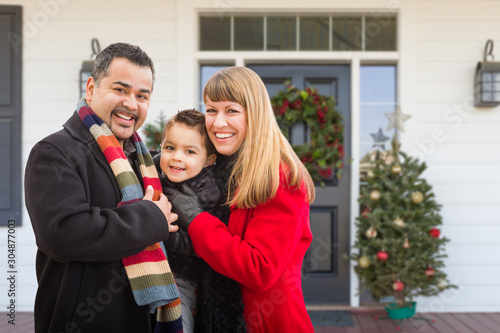 Young Mixed Family On Front Porch of House with Christmas Decorations