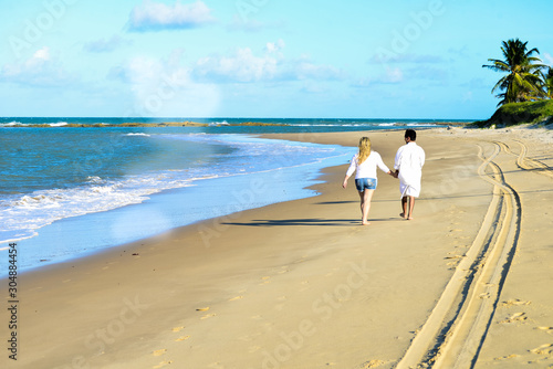 couple holding their hands walking on the beach, Valentine's Day