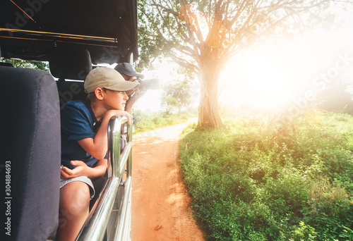 Canvas Print Little expiorer boy portrait with his father taking  of wild animals photos with modern camera with telephotolens as they enjoying auto safari