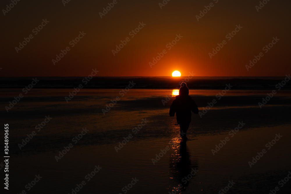 a child watches the sunset on a sandy beach in tofino vancouver island