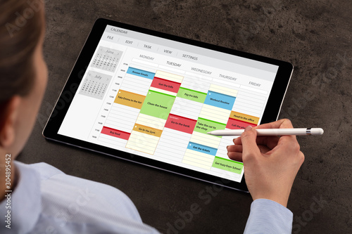 Business woman schedule her weekly program on tablet photo