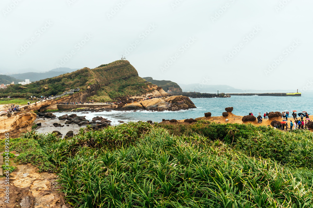 Aerial view diversity of tourists walking in Yehliu Geopark, a cape on the north coast of Taiwan. A landscape of honeycomb and mushroom rocks eroded by the sea.