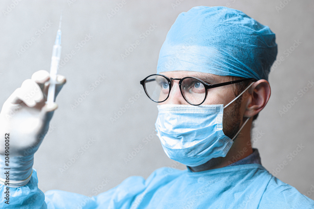 young male surgeon doctor in uniform with a syringe is preparing for injection. young male surgeon doctor in uniform with a syringe is preparing for injection.