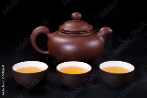 Chinese clay teapot and ceramic tea cups on a black background.