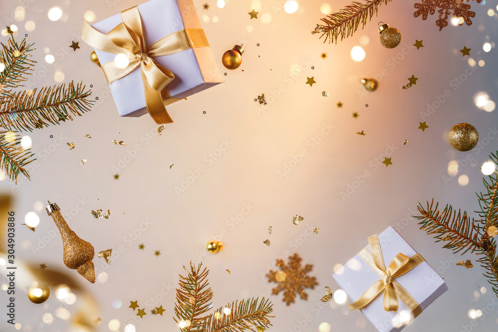 Merry Christmas and New Year background. Xmas holiday card made of flying decorations, gold fir branches, balls, snowflakes, sparkles, gift boxes, bokeh, light on golden background. Selective focus - obrazy, fototapety, plakaty 