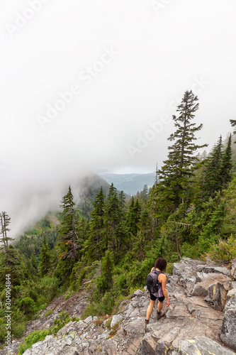 Adventurous Girl is hiking in beautiful green woods in the mountains during a cloudy summer morning. Taken on Crown Mountain, North Vancouver, BC, Canada. © edb3_16