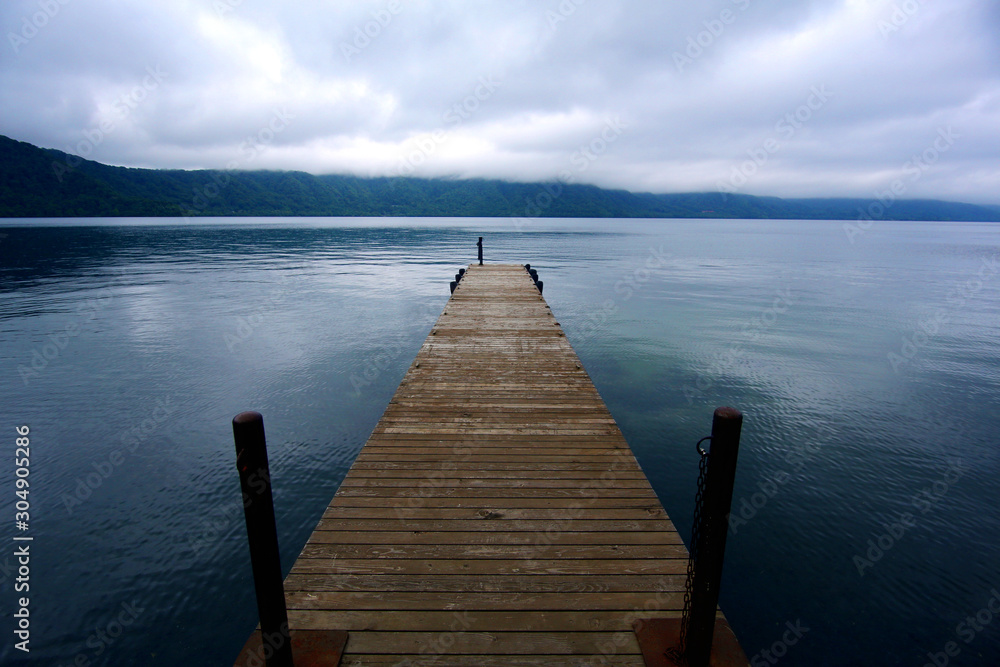 A wooden boardwalk pier extending to the lake, adding more stories to the tranquil lake. Imagine it is very beautiful