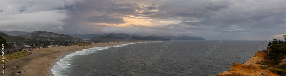 Cape Kiwanda, Pacific City, Oregon Coast, United States of America. Beautiful Aerial Panoramic Landscape View of a Sandy Shore on the Ocean during a cloudy summer sunset.