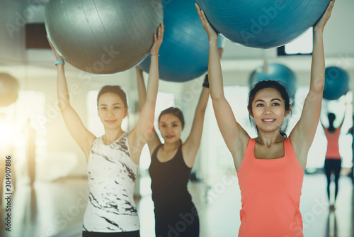 Three healthy Asian women are exercising with yoga ball in the room. photo