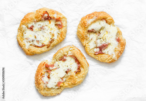 Puff pastry, ham, mozzarella cheese breakfast pizza on a light background, top view