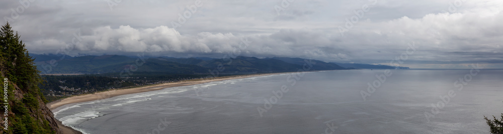Manzanita, Oregon, United States. Aerial Panoramic View of a small town and a sandy beach on the the Pacific Ocean Coast during a cloudy summer day.