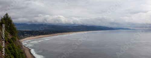 Manzanita, Oregon, United States. Aerial Panoramic View of a small town and a sandy beach on the the Pacific Ocean Coast during a cloudy summer day.