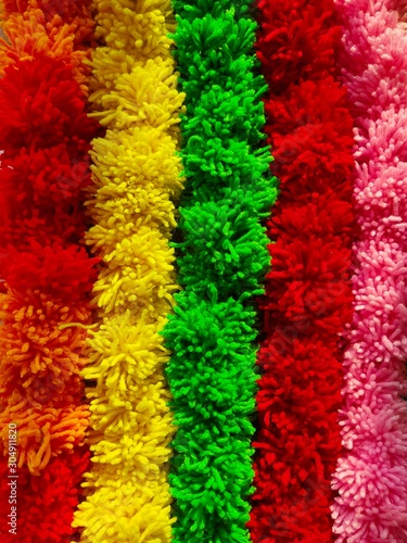 Wool Craft - Background of multicolored pom poms string arranged sideby side photo