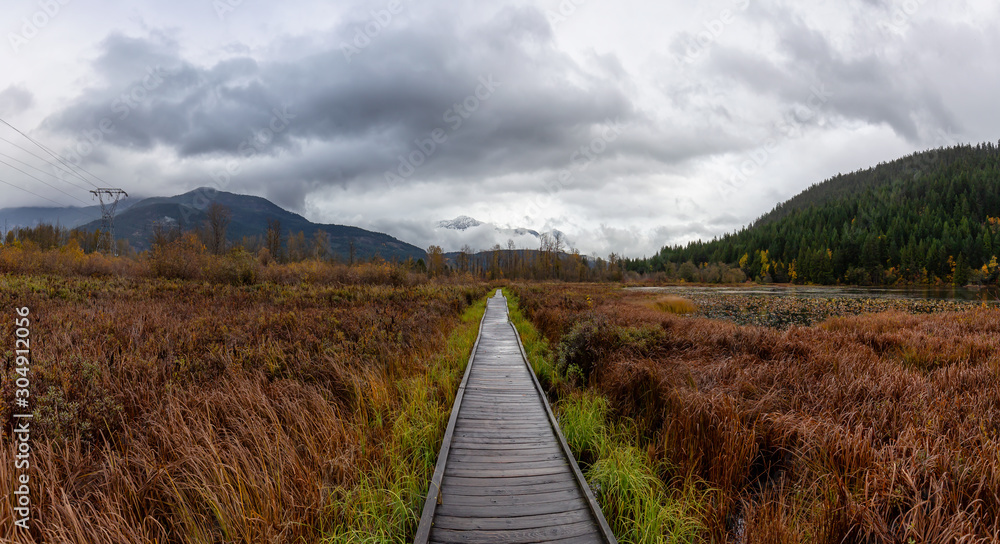 Pemberton, British Columbia, Canada. Beautiful view of a wooden path at One Mile Lake Park during Autumn Season. Pemberton, British Columbia, Canada. Beautiful view of a wooden path at One Mile Lake Park during Autumn Season.