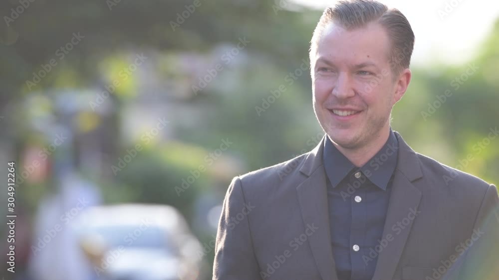 Face of happy young handsome businessman in suit thinking outdoors Face of happy young handsome businessman in suit thinking outdoors