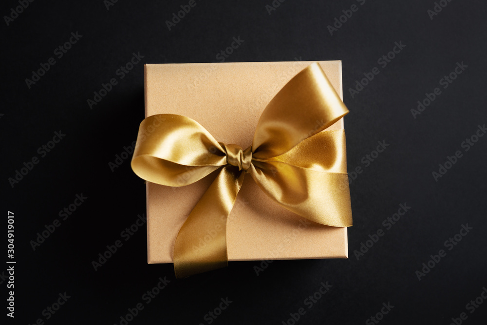 Gift box with golden ribbon on dark background Gift box with golden ribbon on dark background