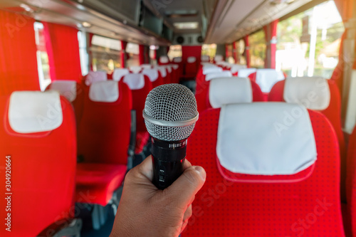 The man holding miceo phone in front of seats in the bus. 