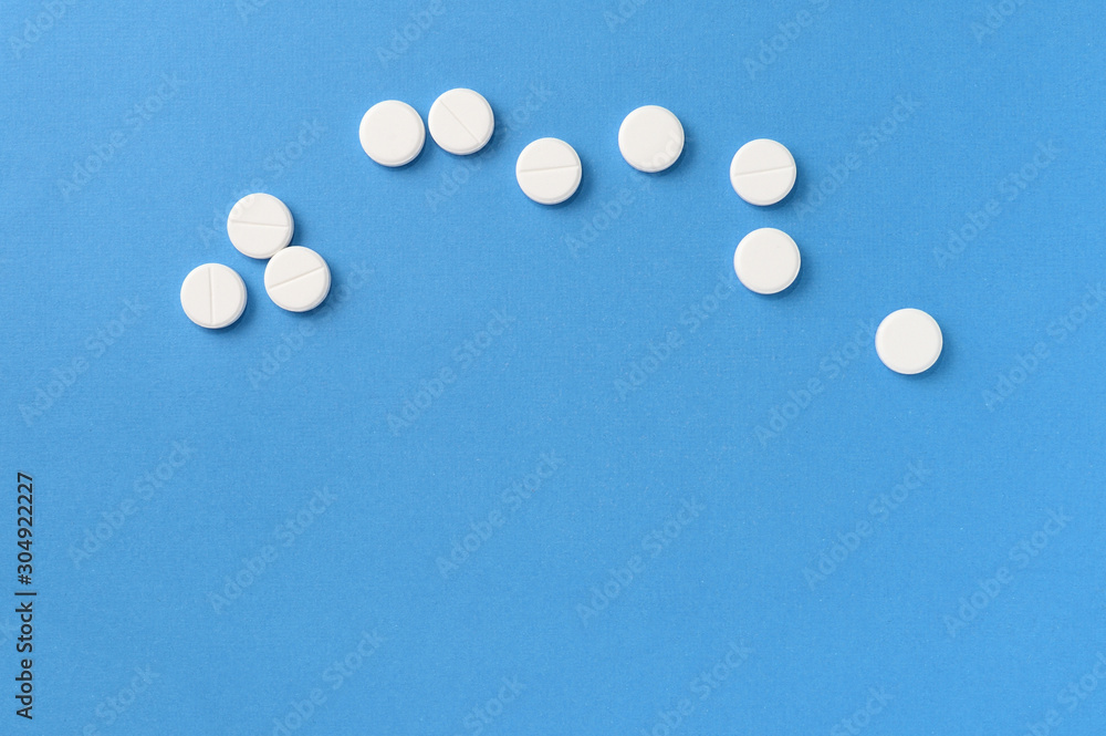 White round pills scattered on a blue background, top view. Medical pharmacy concept White round pills scattered on a blue background, top view. Medical pharmacy concept