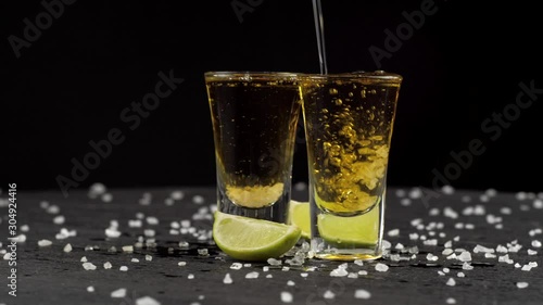 tequila is poured into two glasses on black background photo
