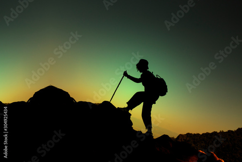 silhouette of people climbing on the mountain over sunset sky background