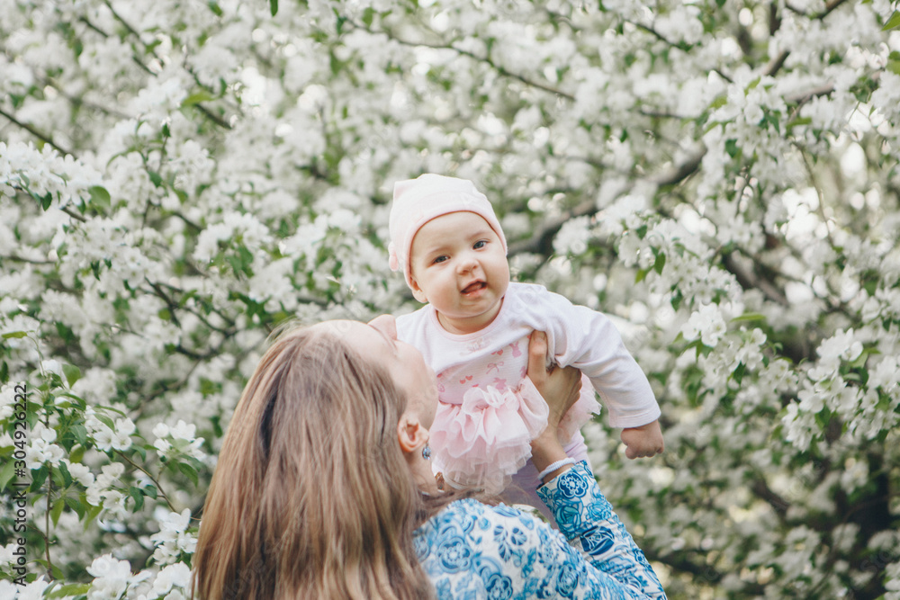 beautiful woman holding children. March 8: women among flowers. the concept of congratulations, women's holidays, natural make up beautiful woman holding children. March 8: women among flowers. the concept of congratulations, women's holidays, natural make up