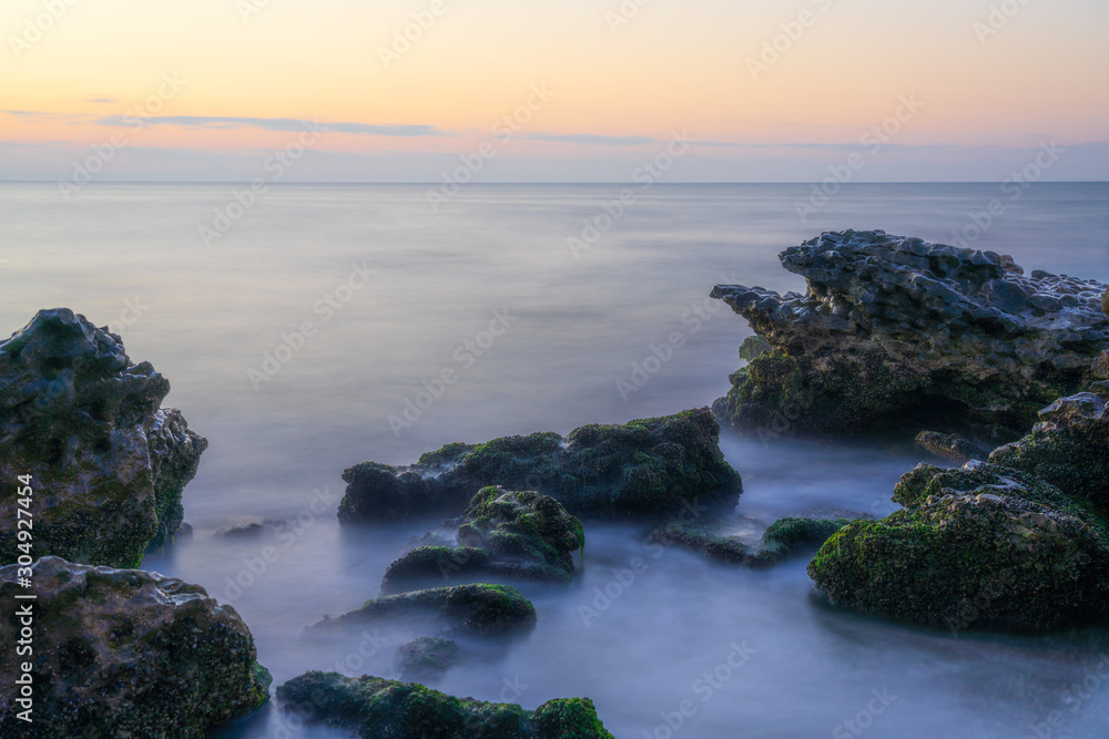Colorful dawn on a rocky seashore, long exposure photography