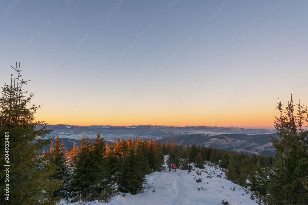 Traveling tourists on the snowy winter mountain ranges of the Ukrainian Carpathians with beautiful views of the evening peaks. Traveling tourists on the snowy winter mountain ranges of the Ukrainian Carpathians with beautiful views of the evening peaks.