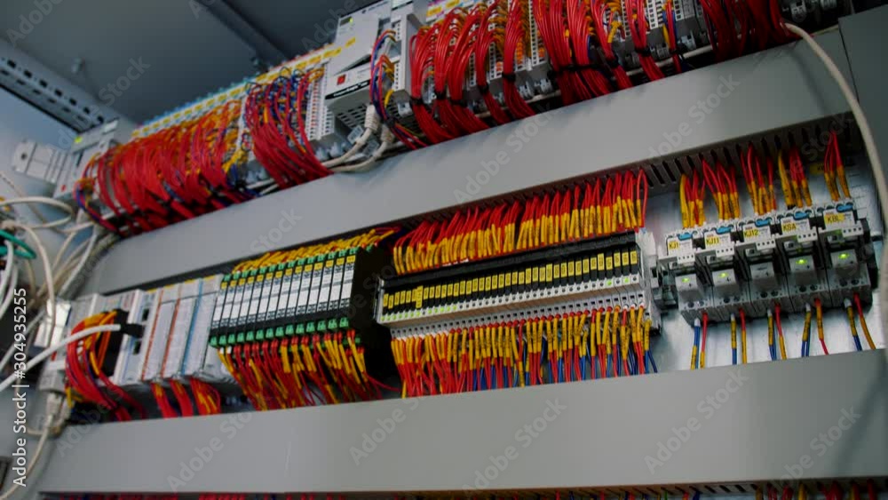 Inside of electrical control panel with multiple switches, wires, short