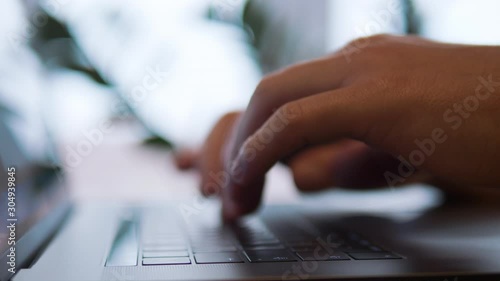Closeup man hands typing message on the keyboard sitting at the table using laptop for chatting with friends at cafe. Indoor shot filmed in 4k UHD Slow motion
