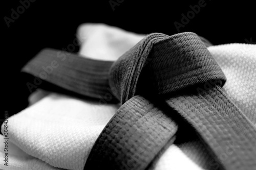 Black judo, aikido or karate belt on white budo gi. Concept is applicable to sports, business or education photo