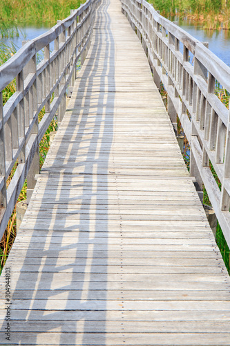 Walkway or walk path wooden bridge in lake swamp or river.
