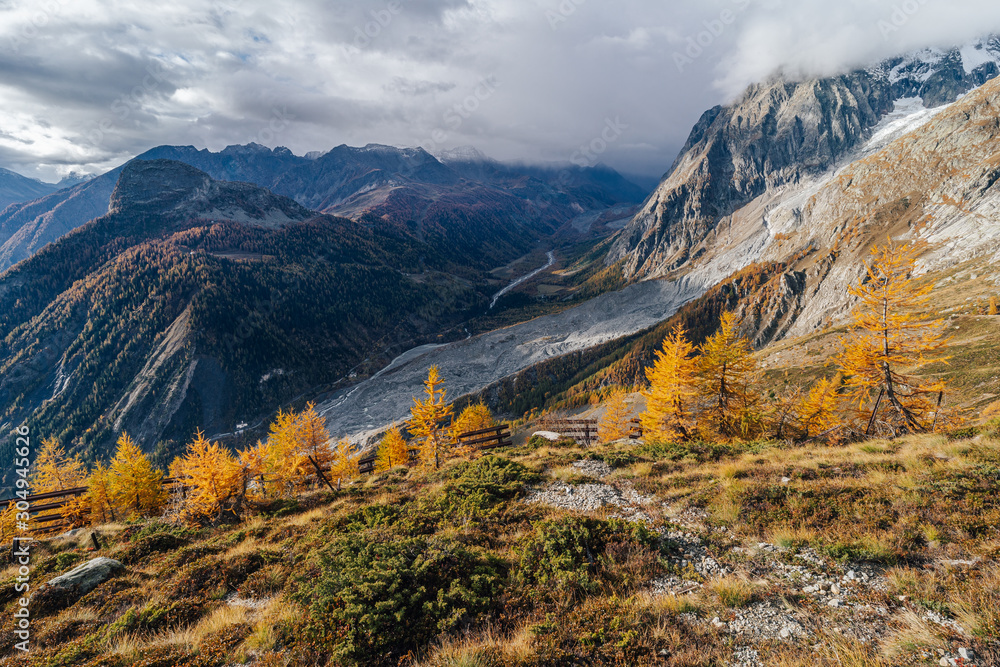Fantastic autumn mountain landscape. Late fall in the mountians. Yellow grass, meadows and high peaks covered with snow. Autumn in Chamonix and Courmayer area, Mont Blanc, Alps. Beautiful autumn day.