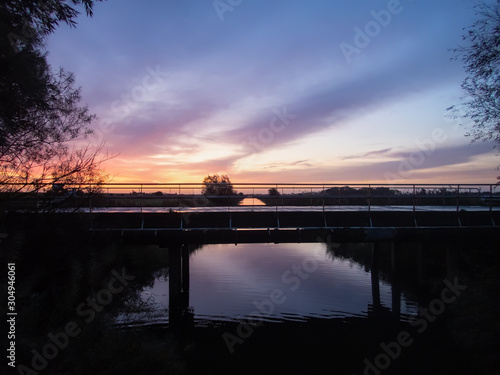 View of a colorful sunrise on a bridge on the coast of the Wadden Sea in Dornumersiel in Germany in Autumn