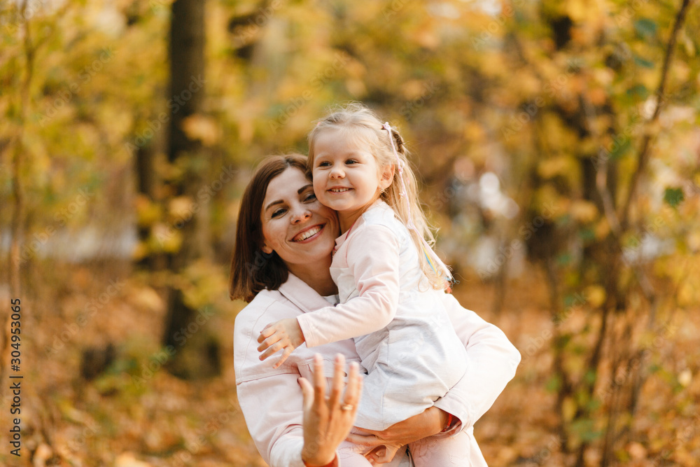 Smiling mother and daughter's portrait in autumn park Smiling mother and daughter's portrait in autumn park