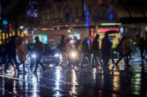 pedestrians crossing street on rainy night in the city