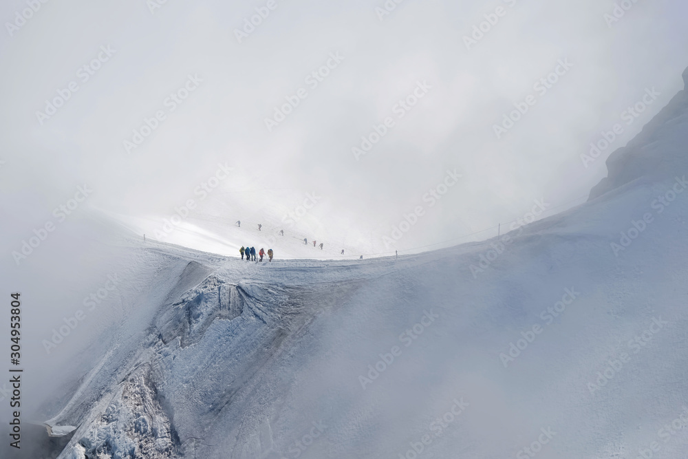 Obraz premium Small figures of alpinists going to Mont Blanc sthrough the snow