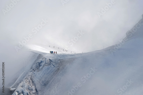 Small figures of alpinists going to Mont Blanc sthrough the snow