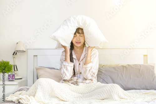 Sleepy young beautiful asian woman wake up unhappy in the morning. Tired attractive teenage girl wake up and sitting the bed.