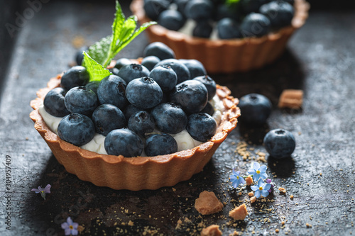 Freshly baked mini tart with blueberries and whipped cream photo