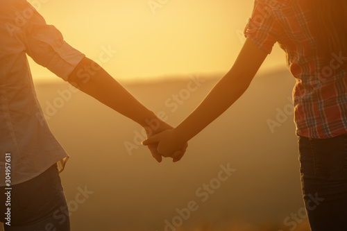 Grandmother and granddaughter holding hands and enjoying sunset.