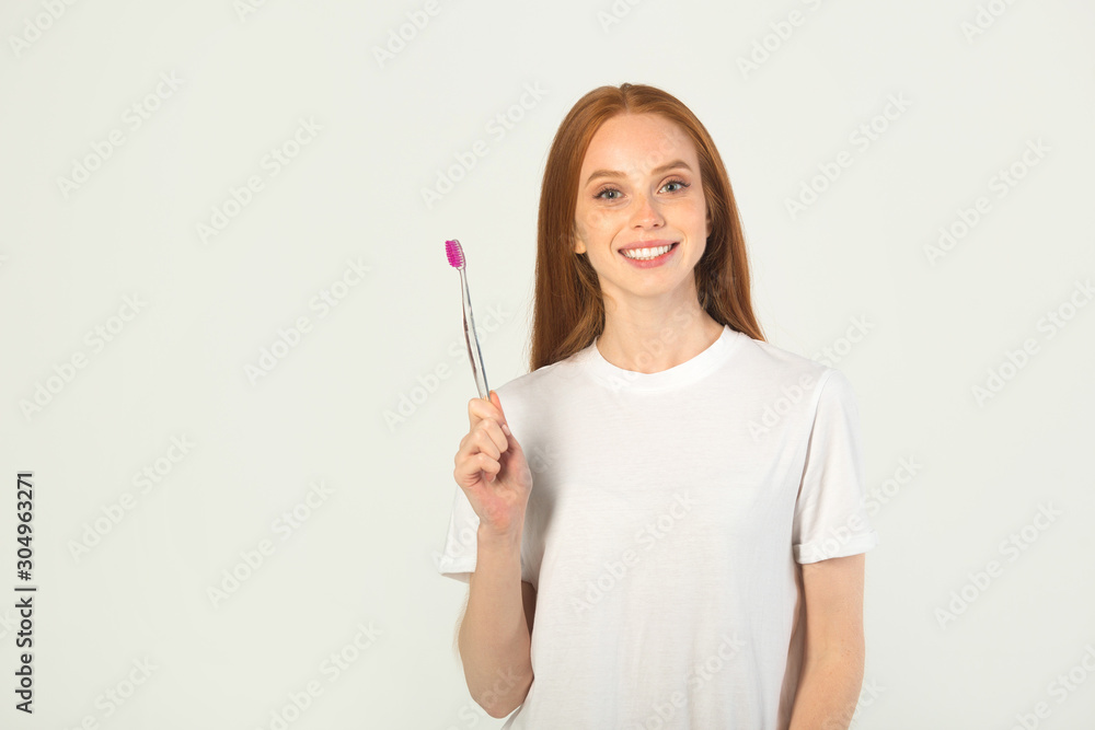 beautiful young woman in a white t-shirt with a toothbrush in her hands beautiful young woman in a white t-shirt with a toothbrush in her hands