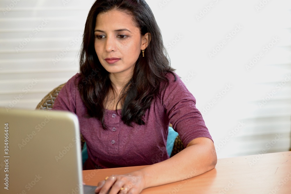 A beautiful office girl sitting in office working on laptop. She is looking confident wearing red colour top and eyewear. A beautiful office girl sitting in office working on laptop. She is looking confident wearing red colour top and eyewear.