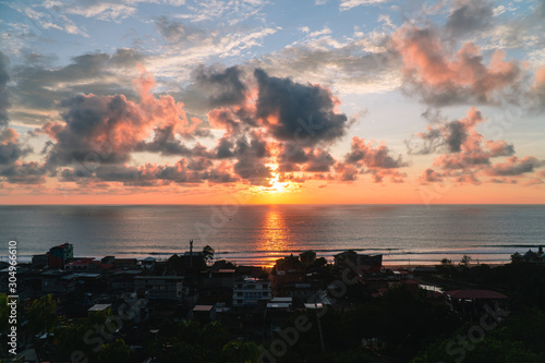 Sunset over beach town. Evening Sky. View of the ocean  sand and rock. Red  pink  orange sky. Dramatic view of Montanita beach town  at sunset.  Montanita  Ecuador