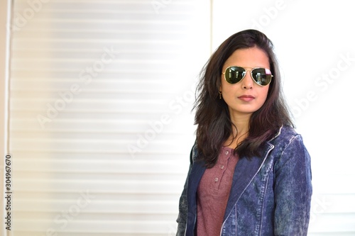 A beautiful and sexy girl is posing wearing blue denim jacket and Sunglasses.  © rajaditya