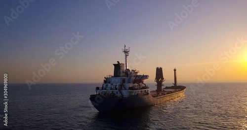 Large Cargo Ship facing Sunrise with flare. © MagioreStockStudio