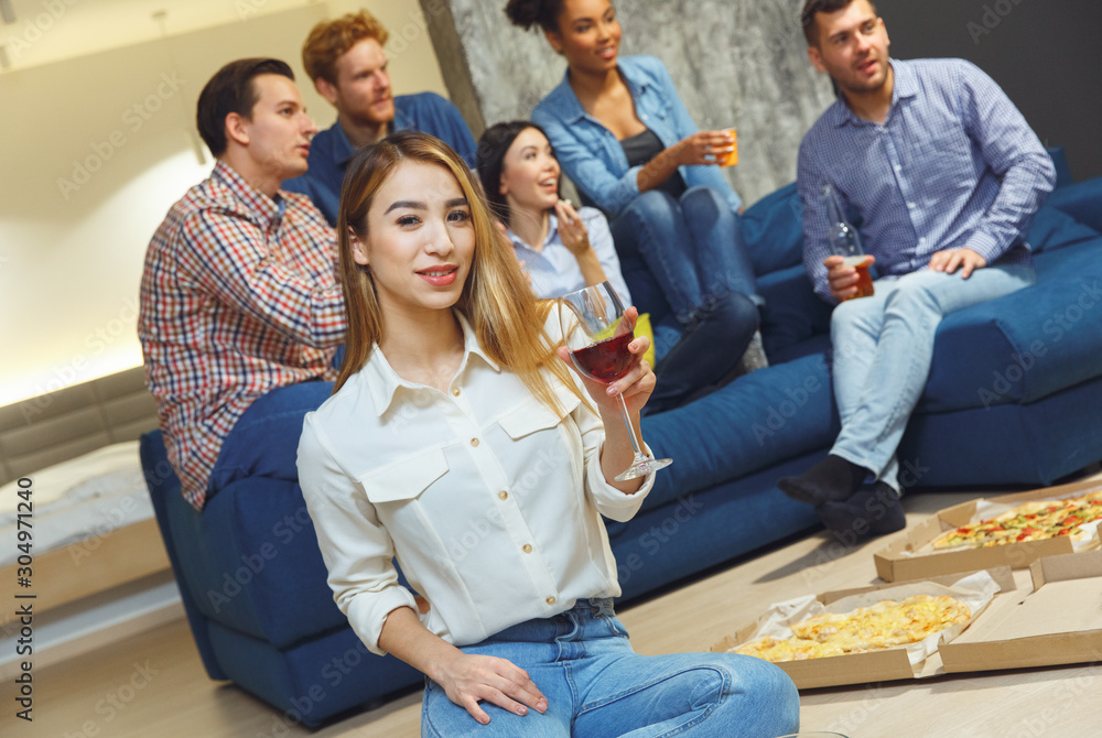 Group of friends having party indoors fun together girl sitting close-up with wine glass Group of friends having party indoors fun together girl sitting close-up with wine glass
